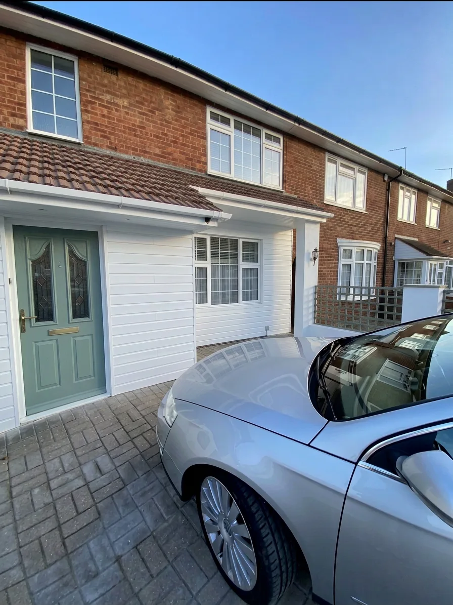 Full property view — white cladding, garage, and clean driveway