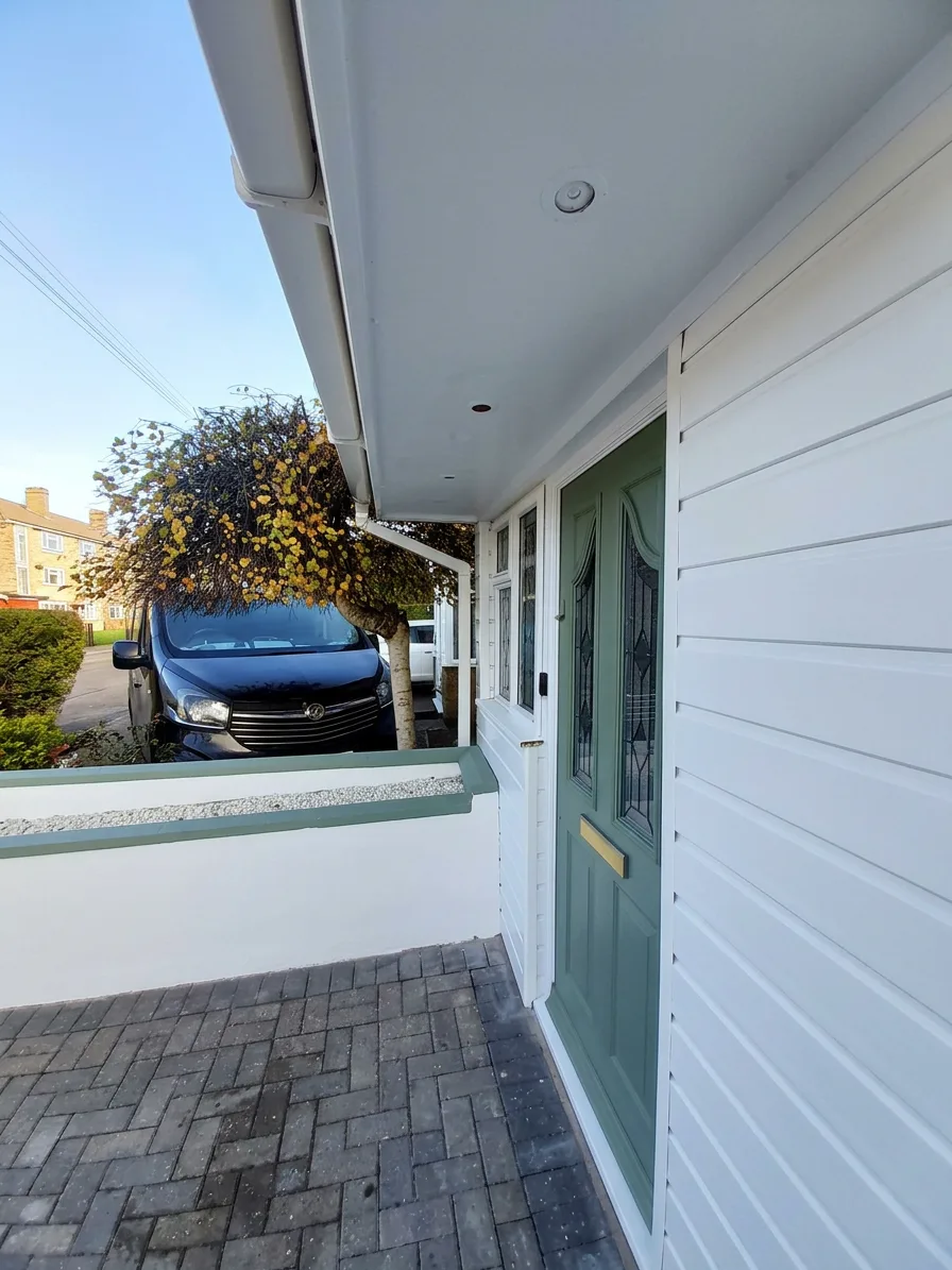 Entrance detail — front door, soffits, and rendered wall